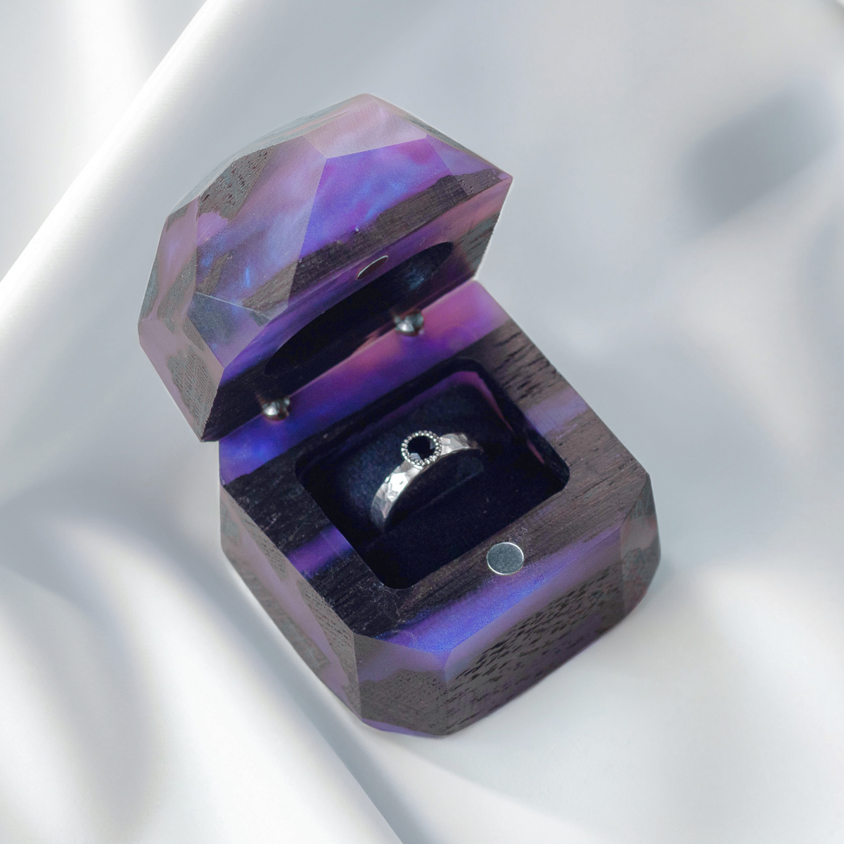 Open purple and bog oak METEORITE box holding a textured silver ring with a dark stone on white satin
