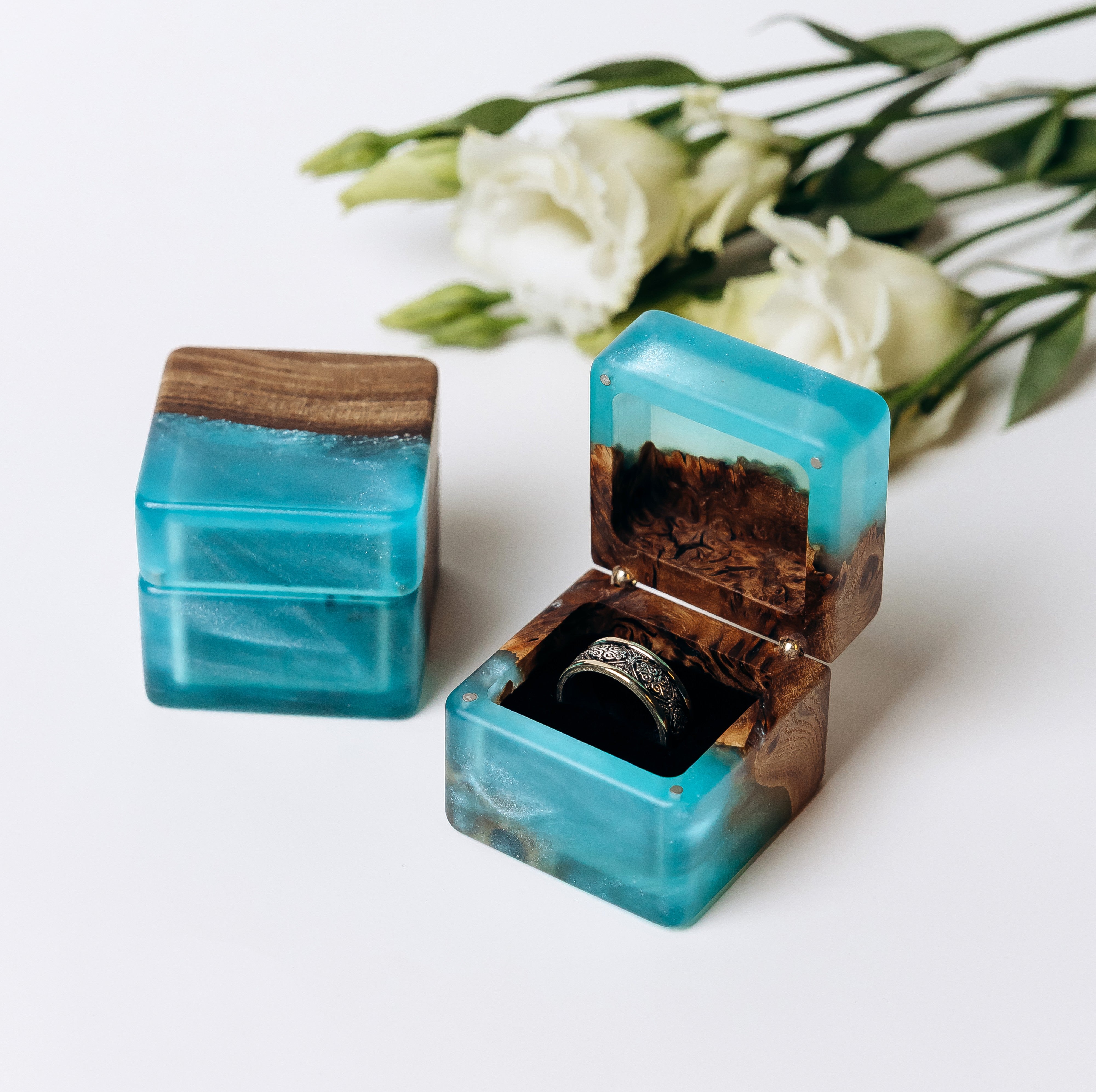 Pair of aqua blue epoxy elm ring boxes, one closed and one open with a ring on the pillow