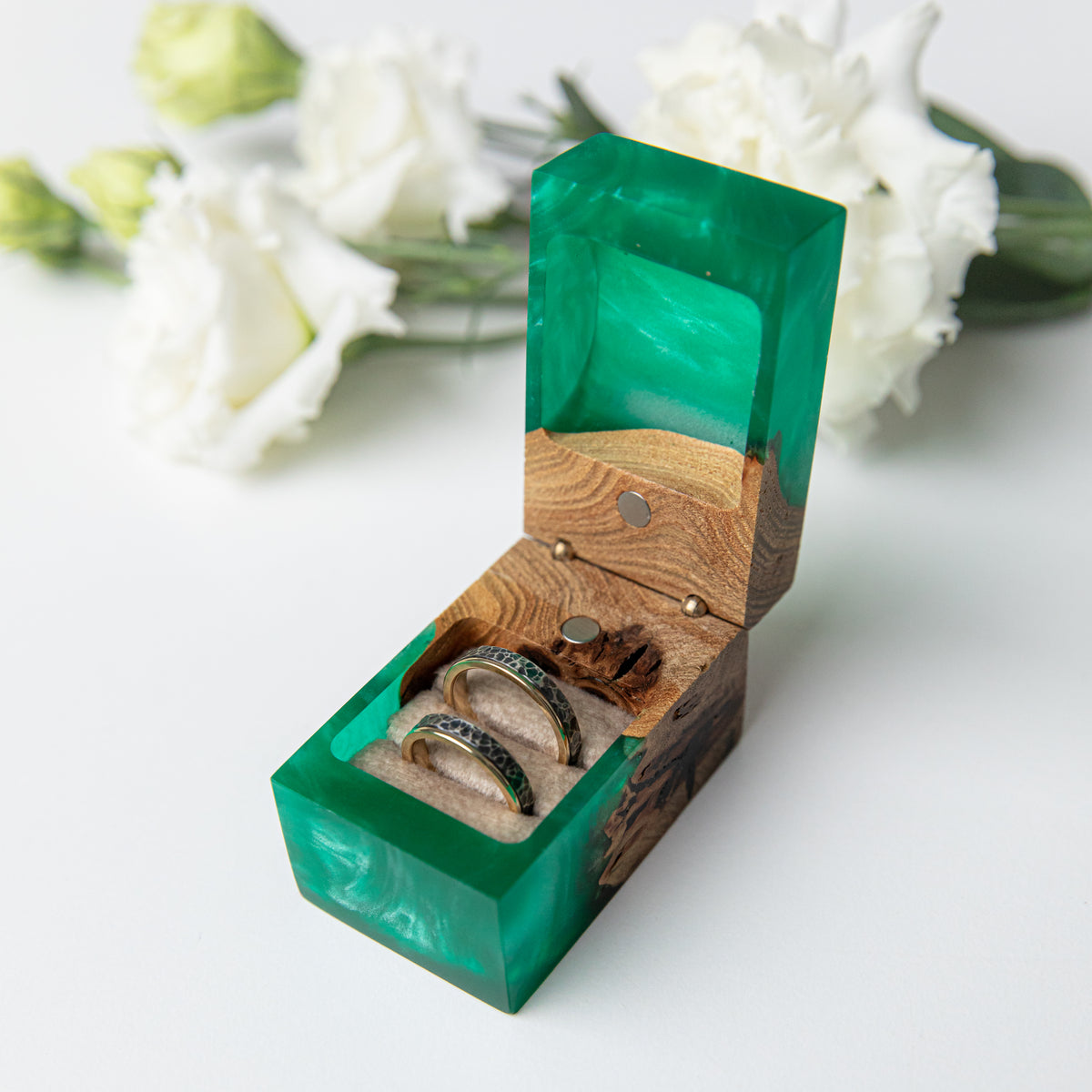 Close-up of two wedding bands in the soft double pillow of the green and elm ring box