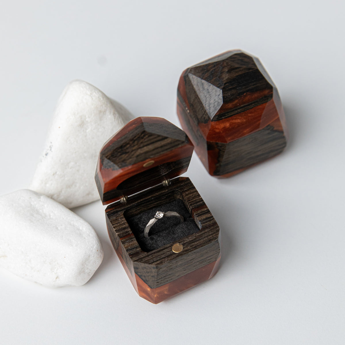 Faceted amber epoxy and bog oak proposal ring box open with a solitaire ring beside white stones