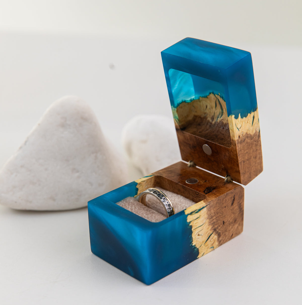 Open blue CHORD engagement ring box with a ring in the soft pillow, white stones behind