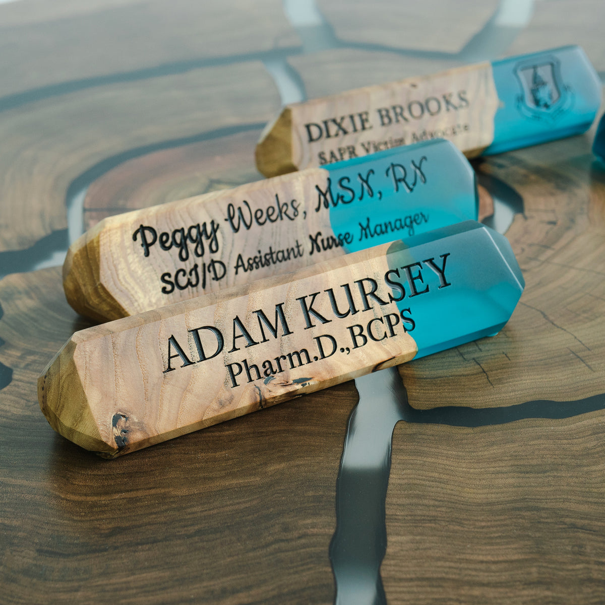 Three engraved aqua blue epoxy name plates for a pharmacist, a nurse manager and an advocate