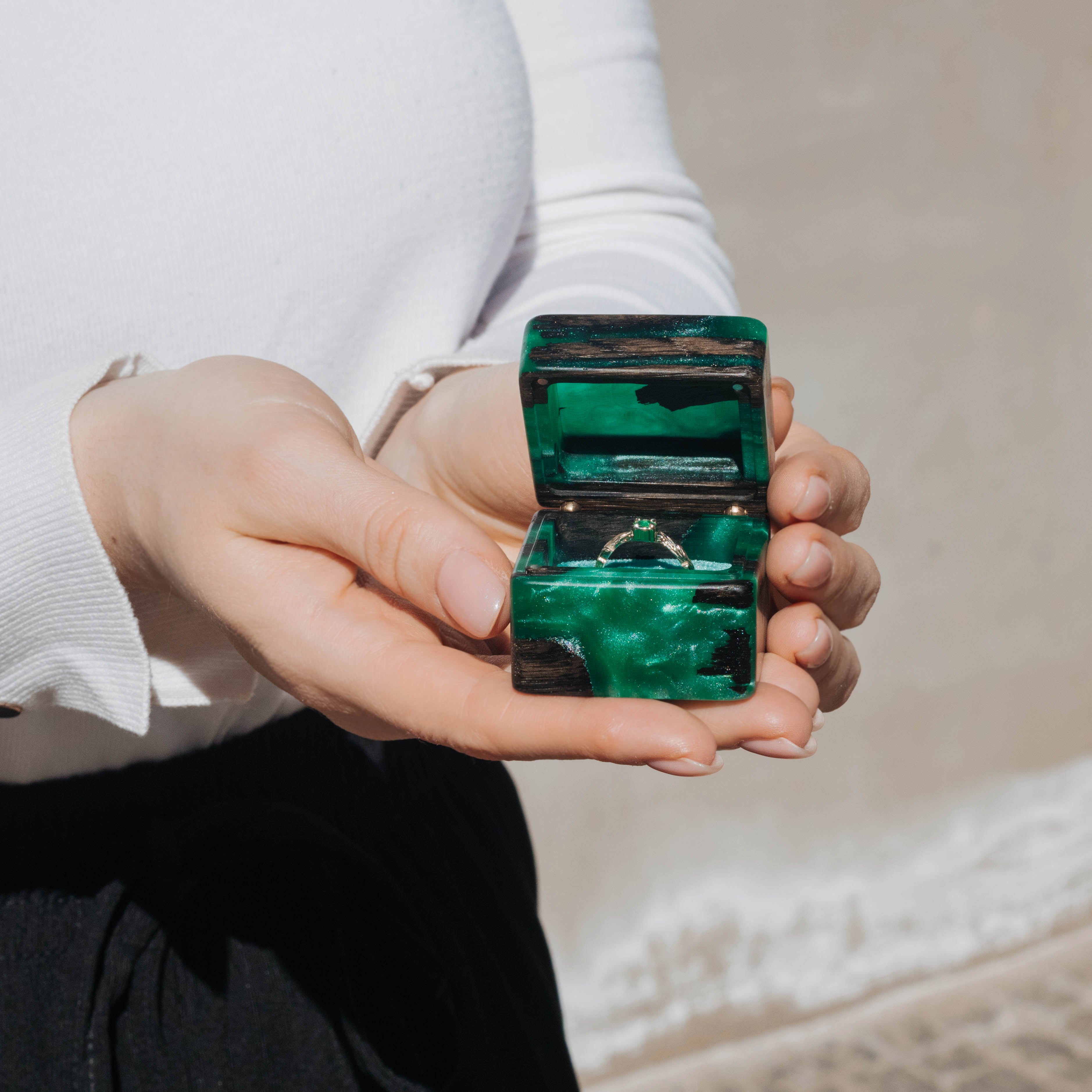 Green epoxy and bog oak wood engagement ring box held in hand for size reference