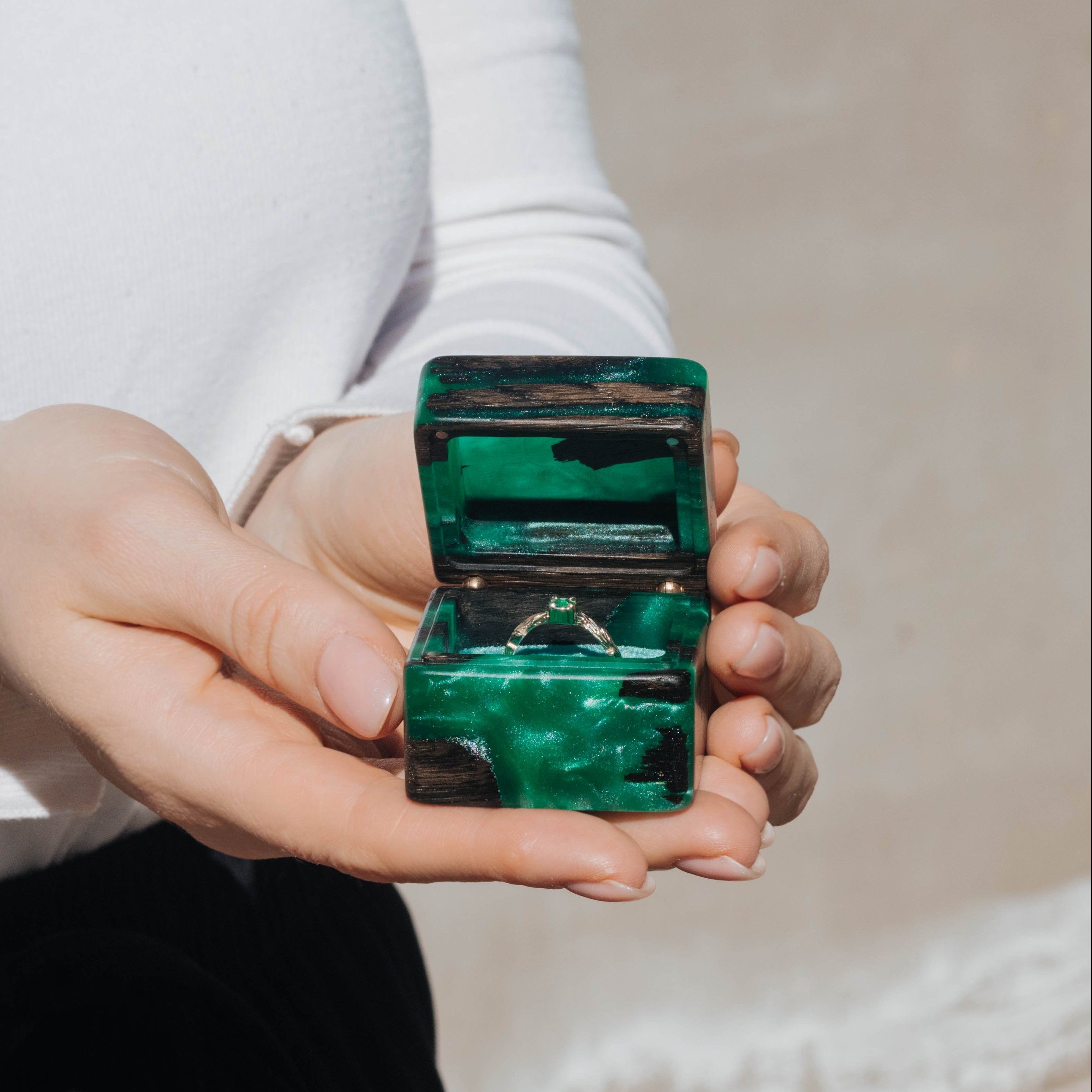Green epoxy and bog oak wood engagement ring box held in hand for size reference