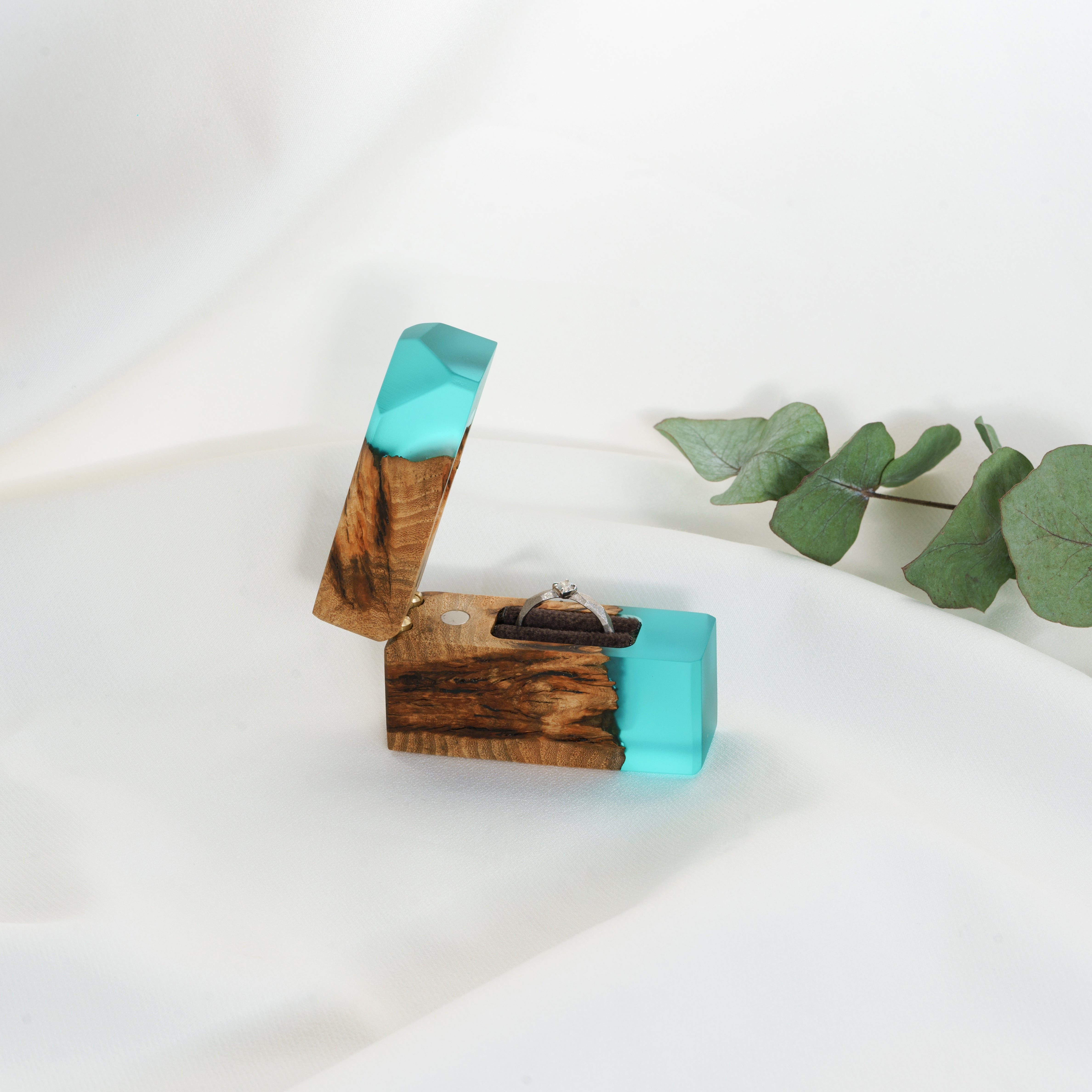 Handcrafted aqua blue epoxy and maple wood engagement ring box photographed from an angled view