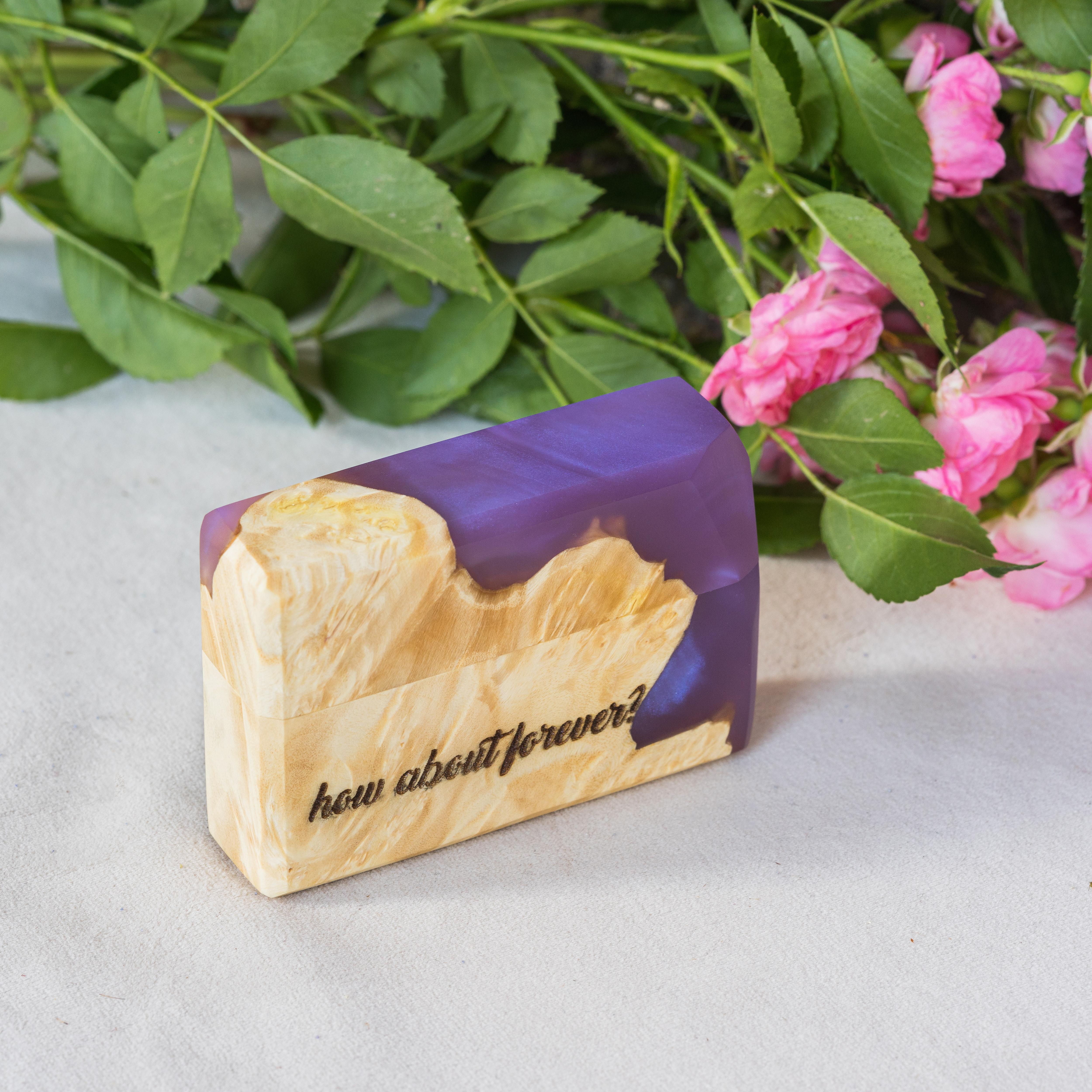 Handcrafted purple epoxy and maple wood engagement ring box photographed in a garden setting