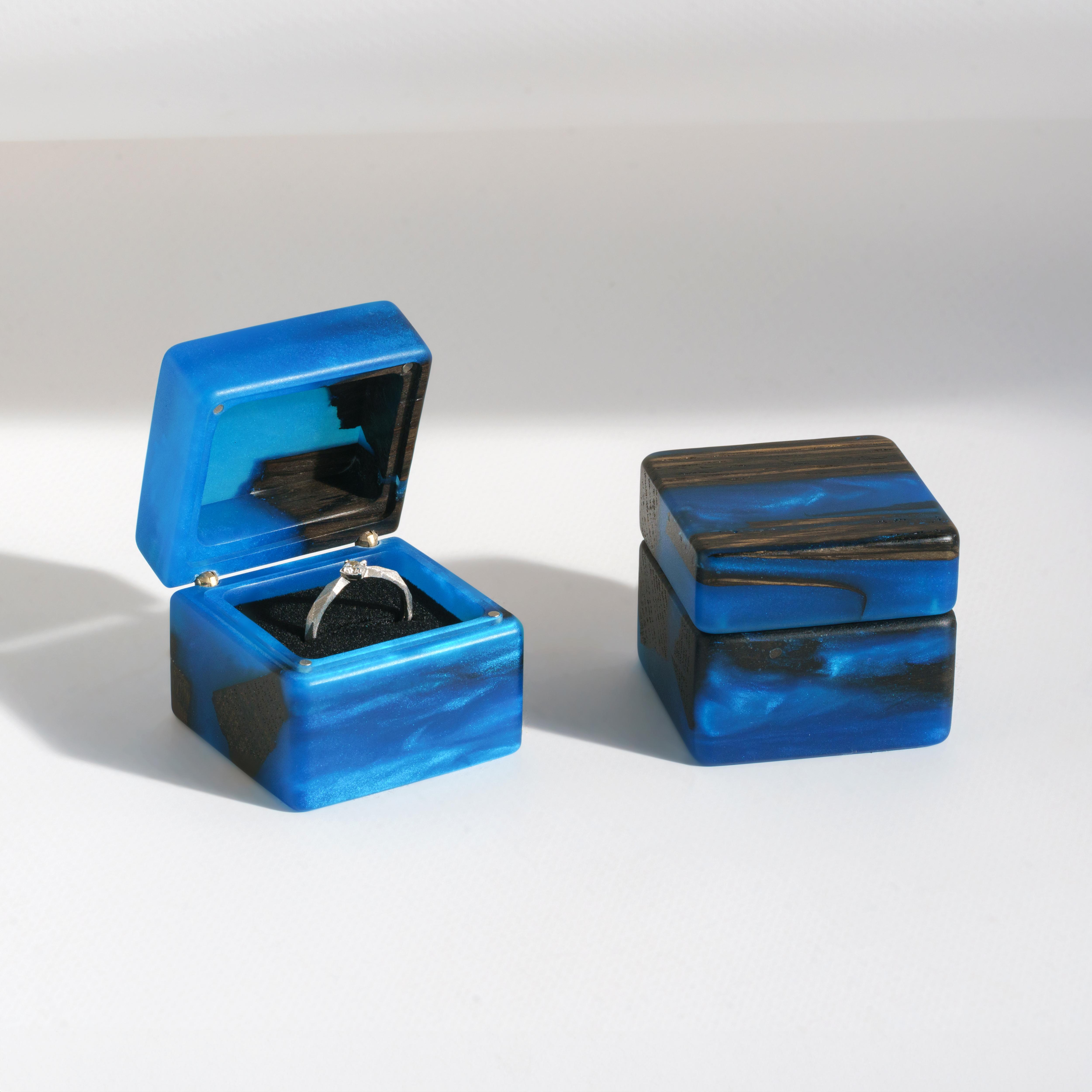 Open engagement ring box handcrafted from blue epoxy and bog oak wood with the matching closed box beside it
