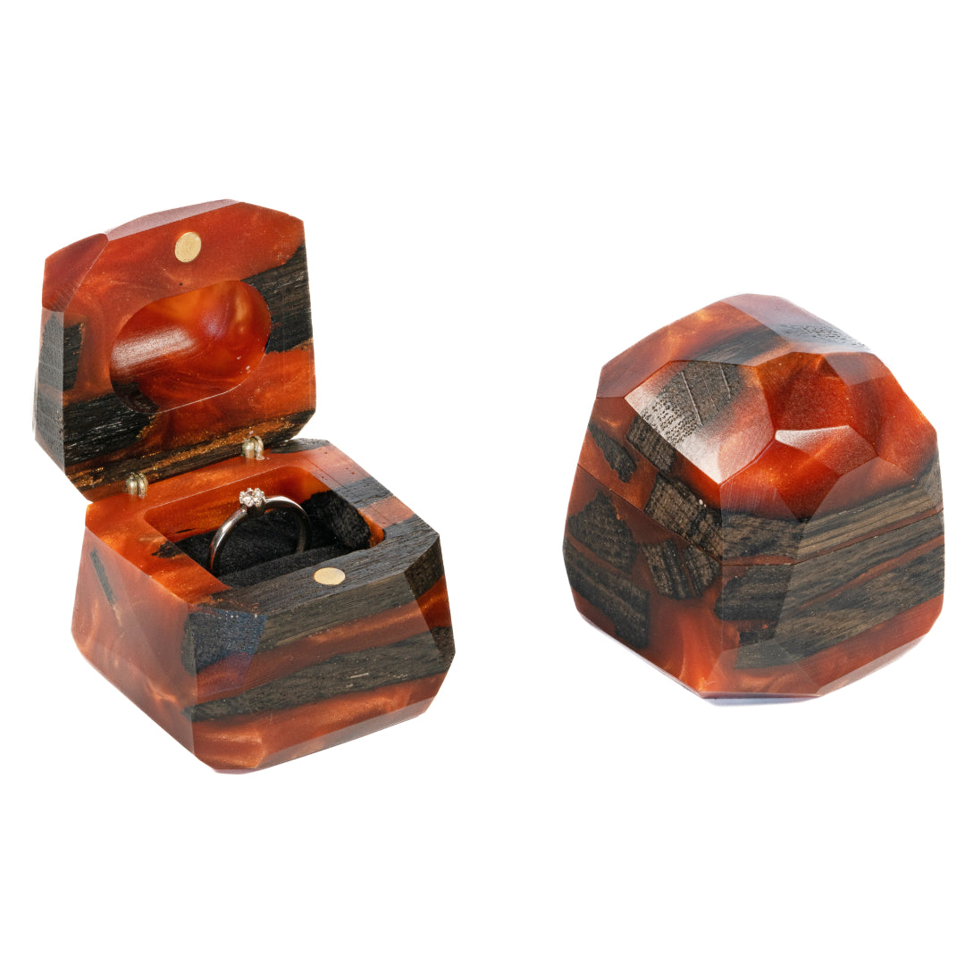 Open and closed amber epoxy and bog oak wood proposal ring boxes displayed together on a white background