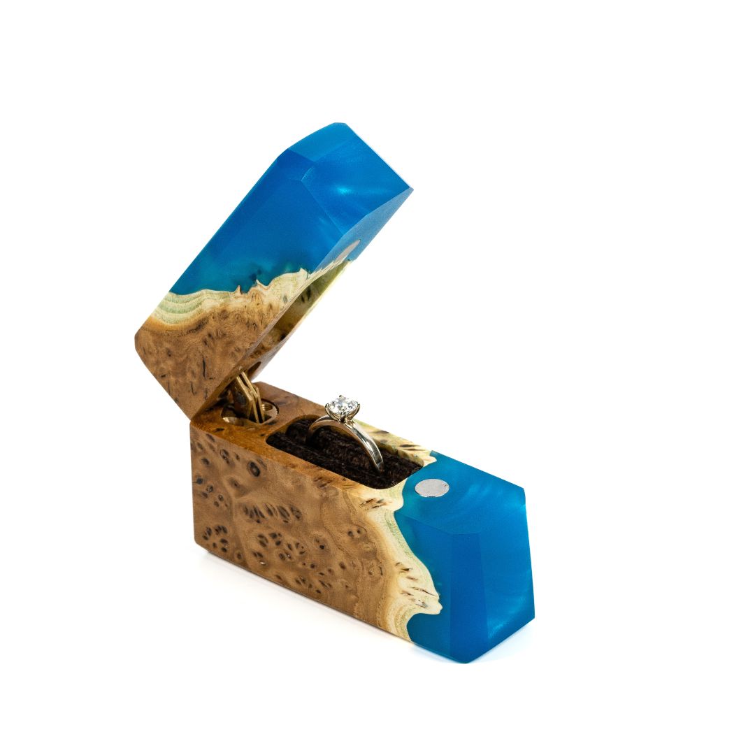 Handcrafted blue epoxy and elm wood proposal ring box photographed from a front angle