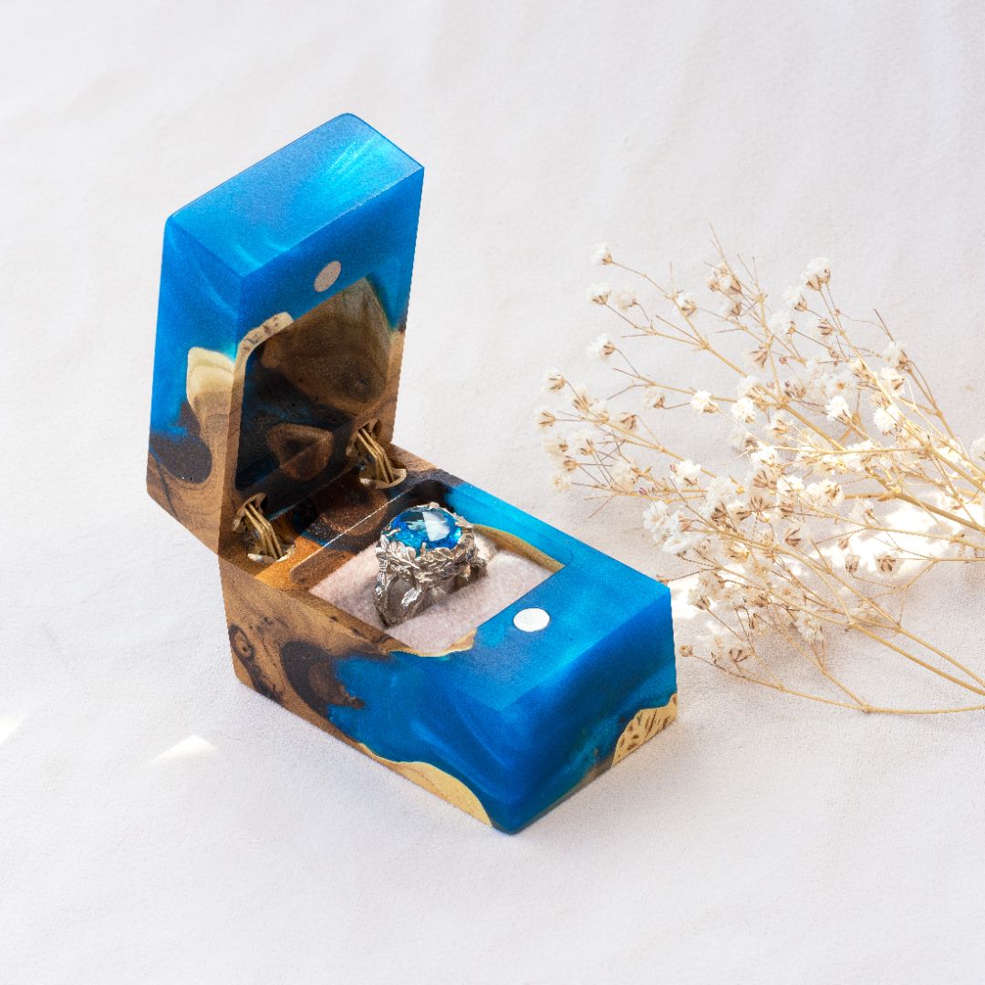 Luxury blue epoxy and elm wood engagement ring box displayed open with delicate dried flowers