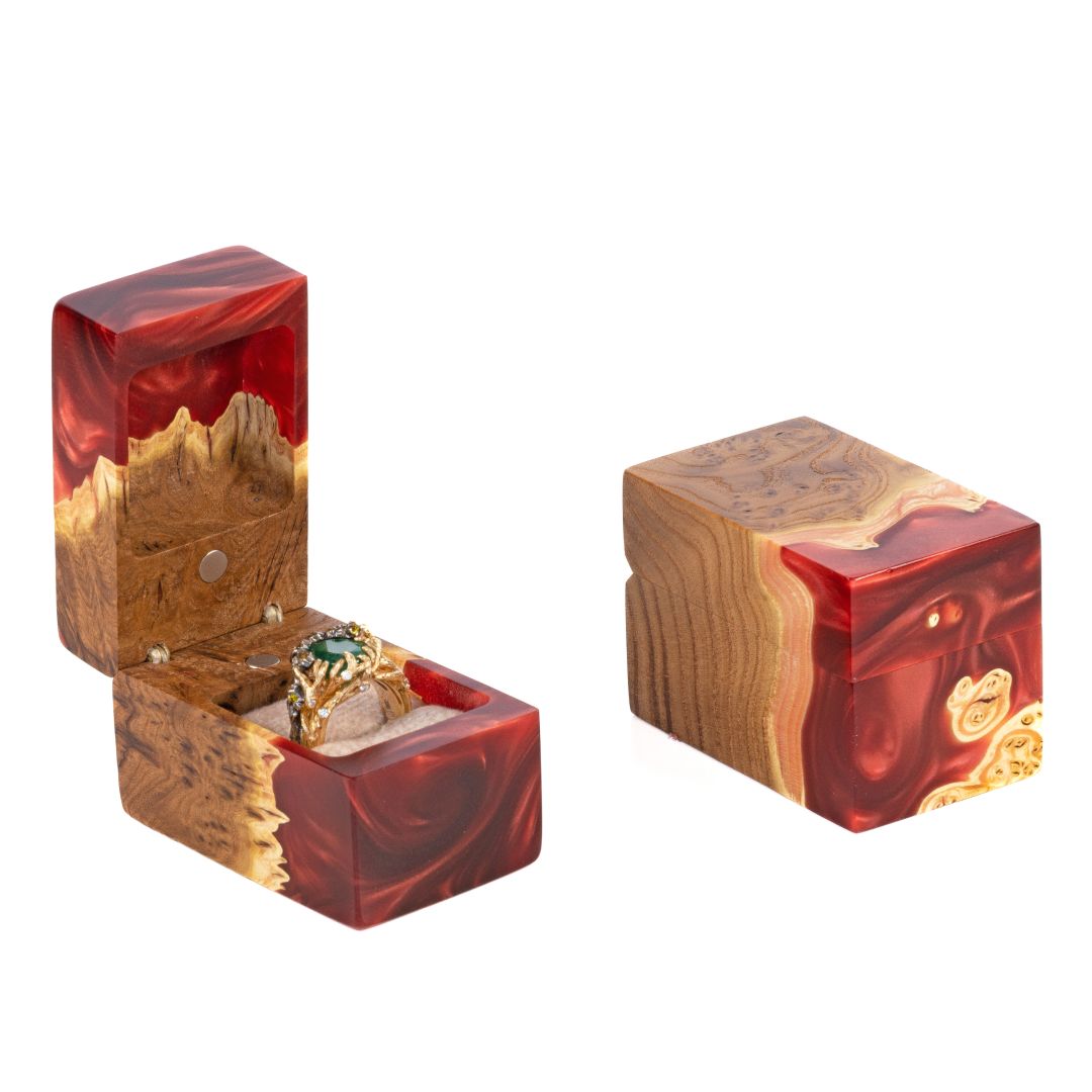 Open and closed ruby epoxy and elm wood engagement ring boxes displayed together on a white background