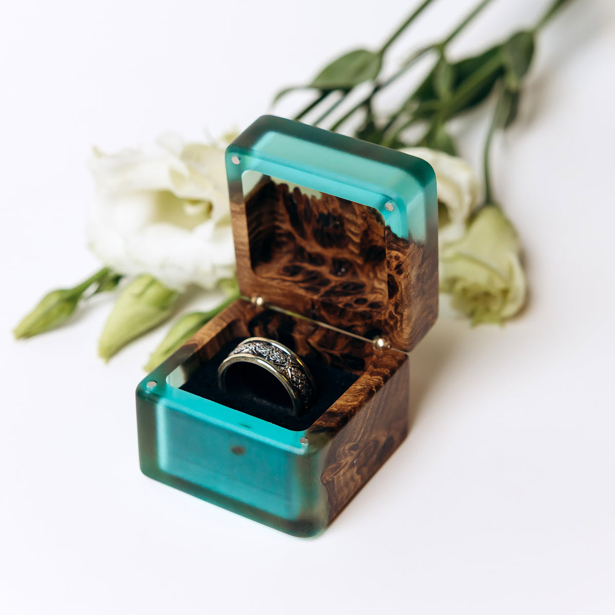Open aqua blue epoxy and elm wood ring box holding a patterned wedding band, MUSE design