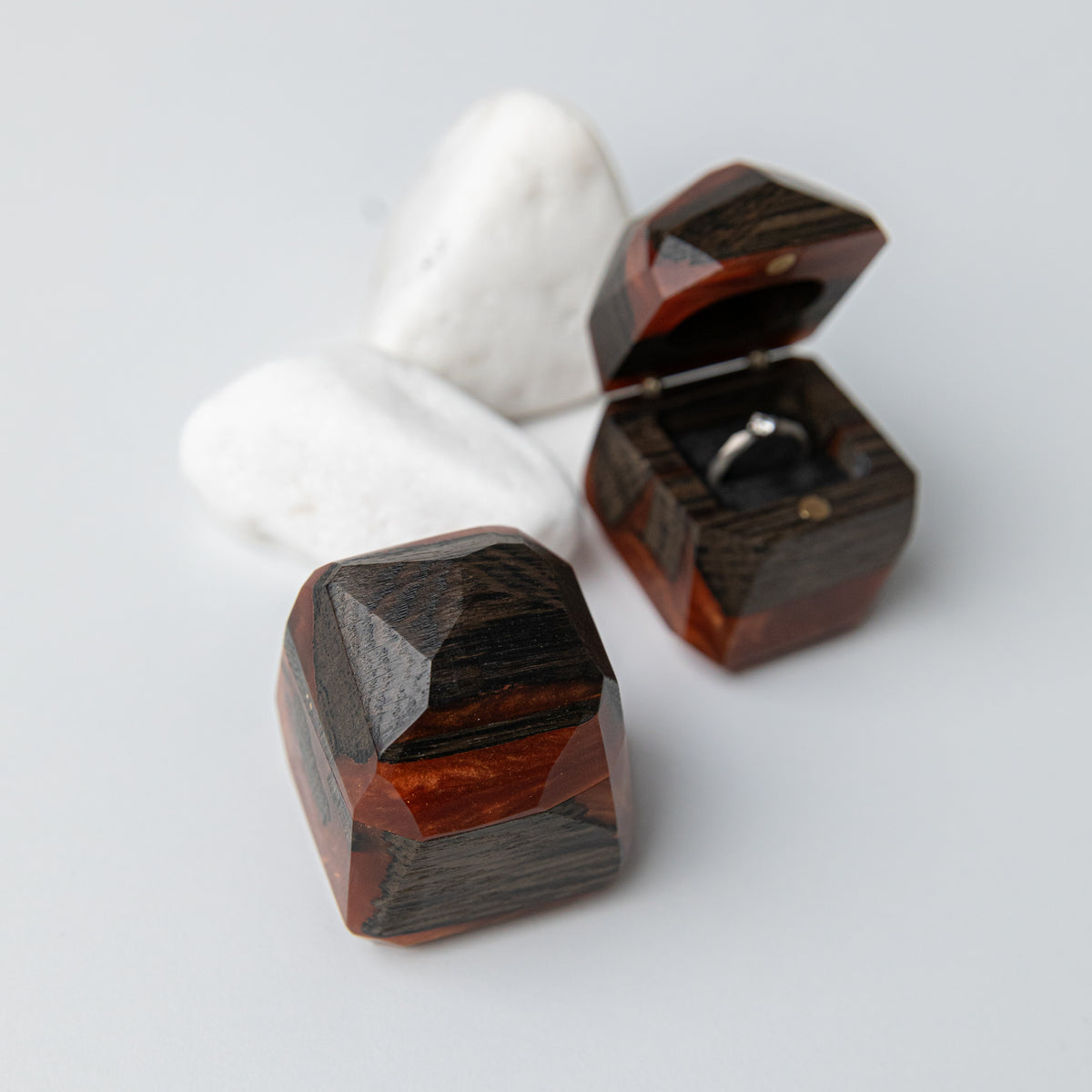 Closed amber and bog oak METEORITE box in front of an open one holding a solitaire ring