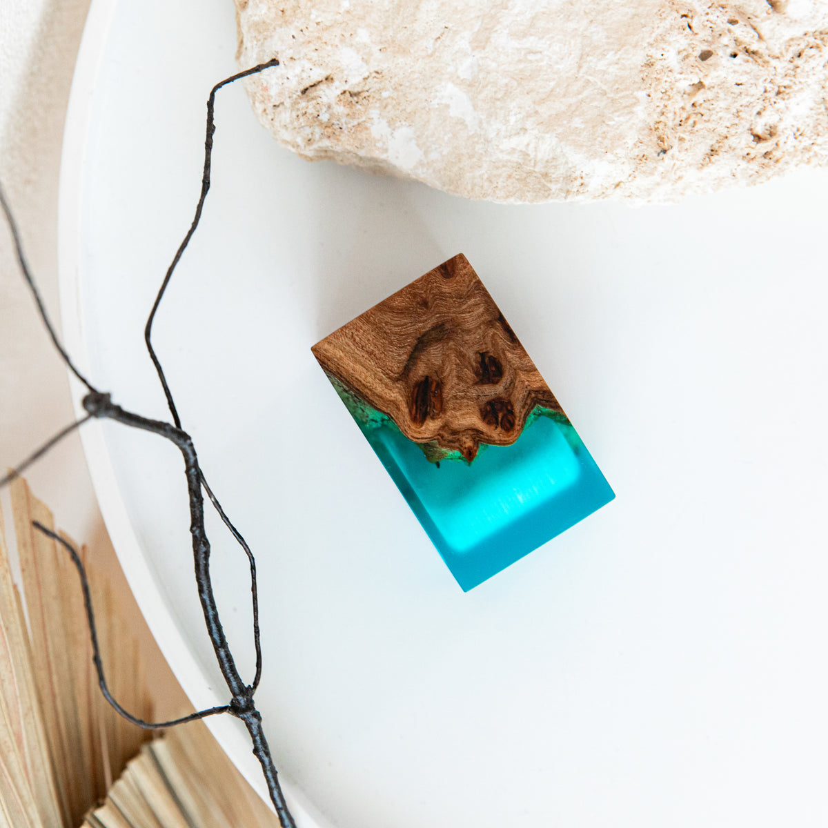 Closed aqua blue and elm ring box seen from above on a white tray with a dark branch