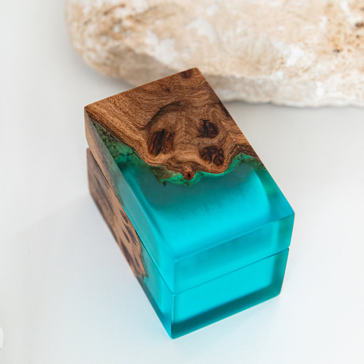 Closed CHORD ring box up close, elm burl flowing into translucent aqua blue epoxy
