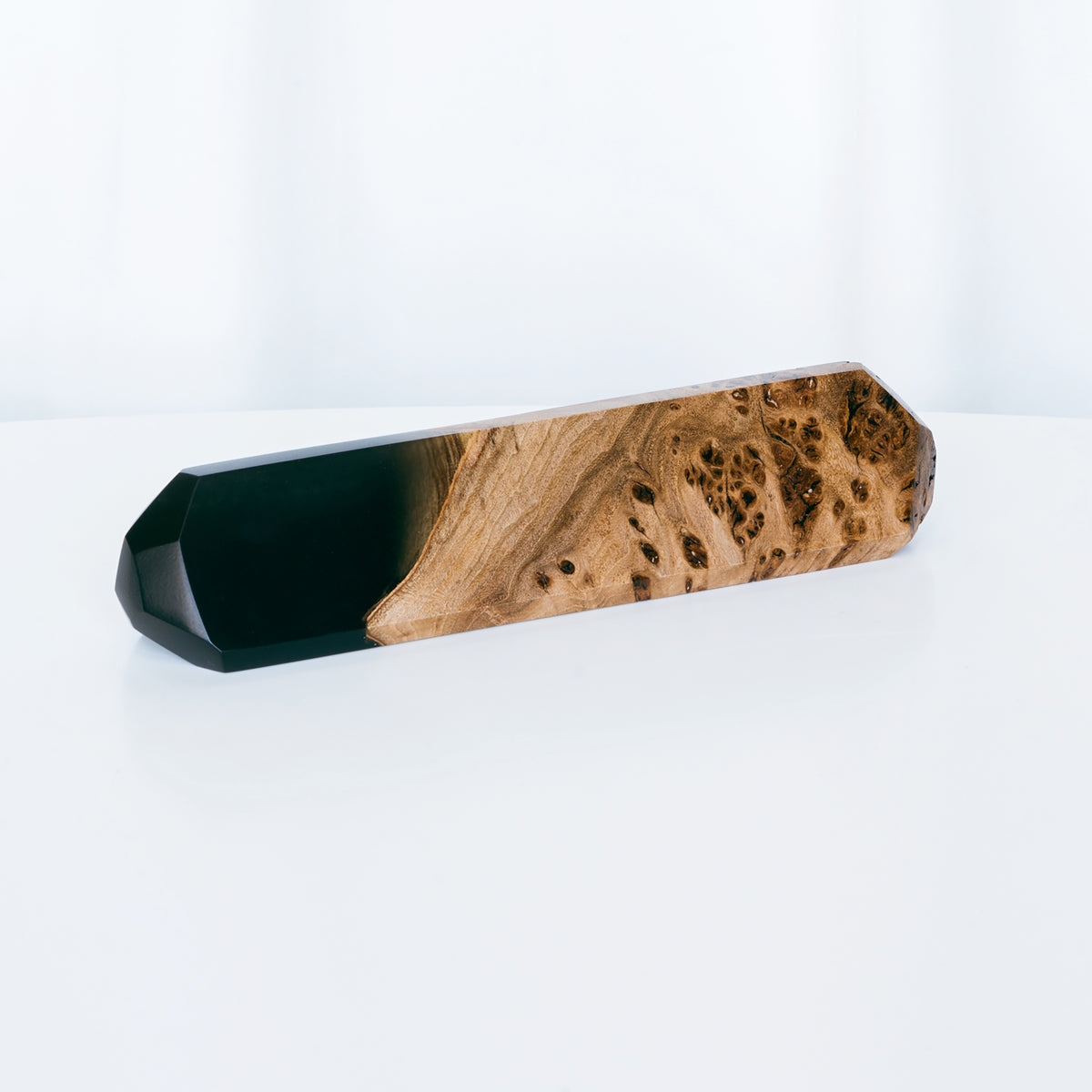Blank faceted IDENTITY name plate in black epoxy and elm burl on a white table, ready for engraving