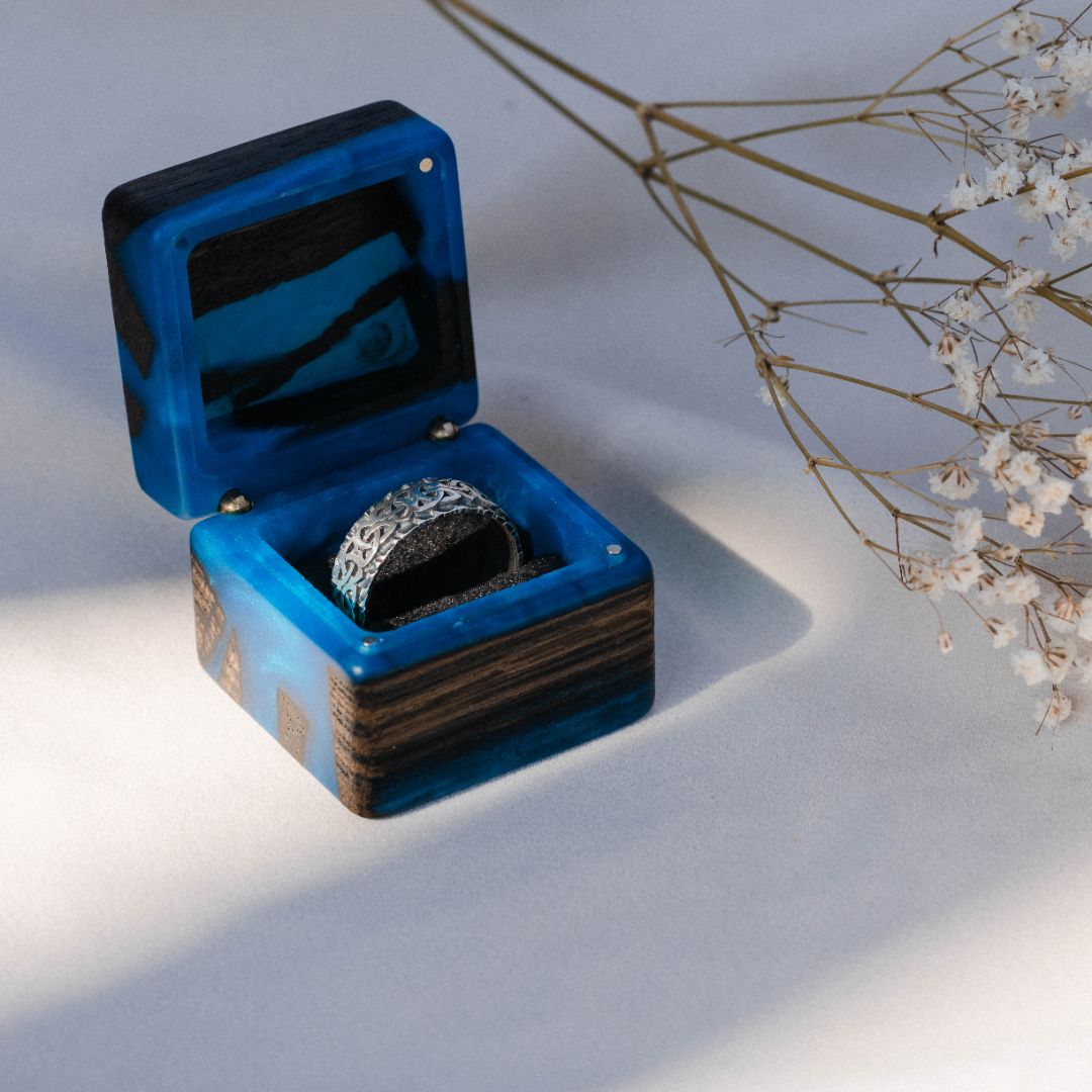 Luxury blue epoxy and bog oak wood engagement ring box displayed open on a white fabric background