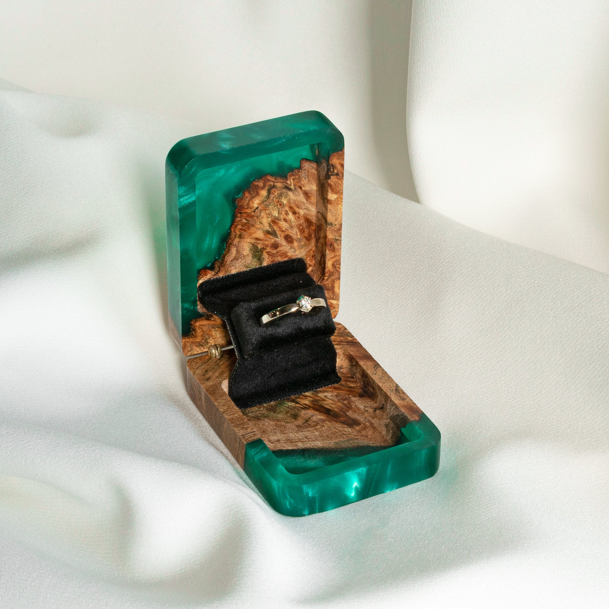 Luxury green epoxy and elm wood engagement ring box displayed open on a white fabric background