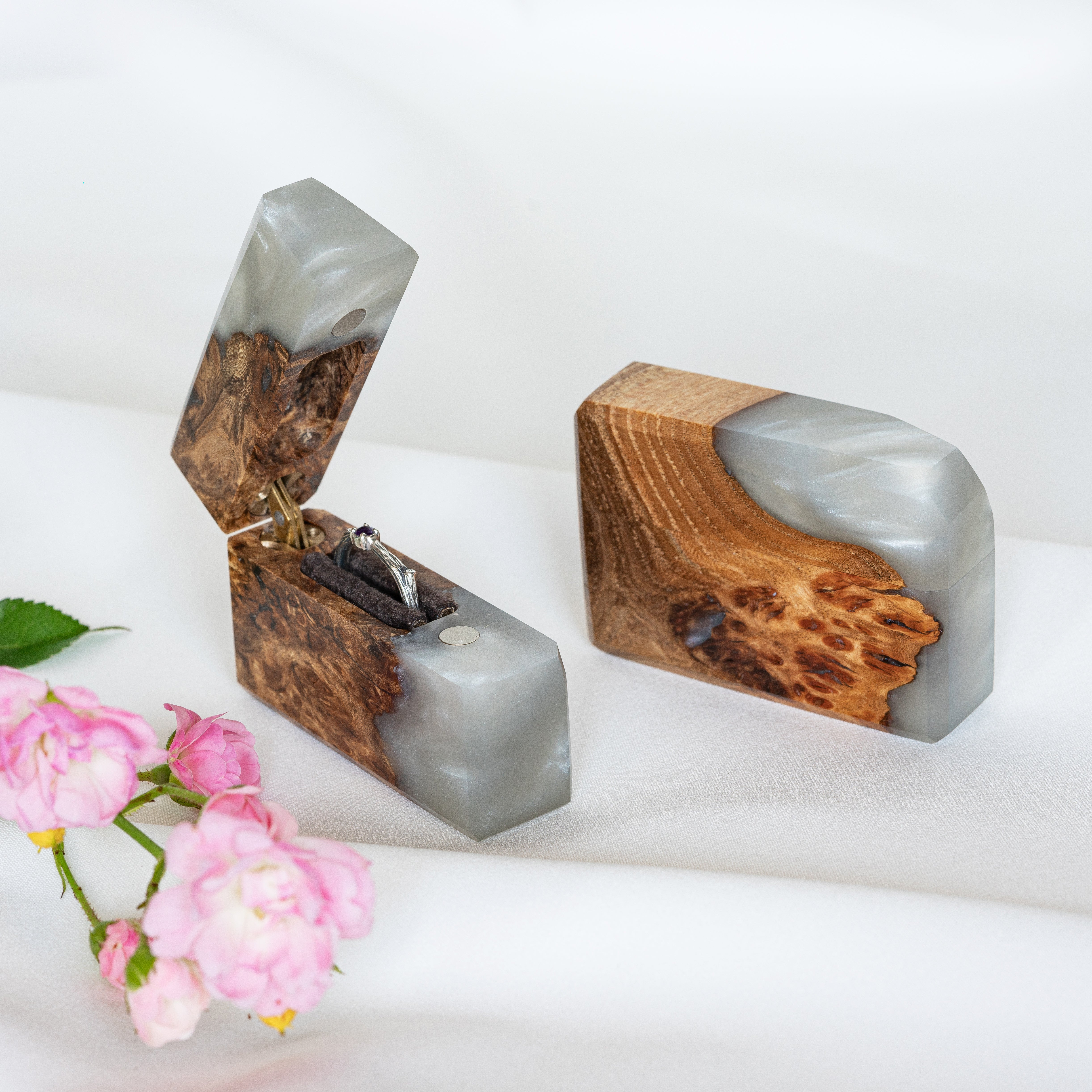 Luxury platinum epoxy and elm wood engagement ring box displayed with floral accents on a white surface