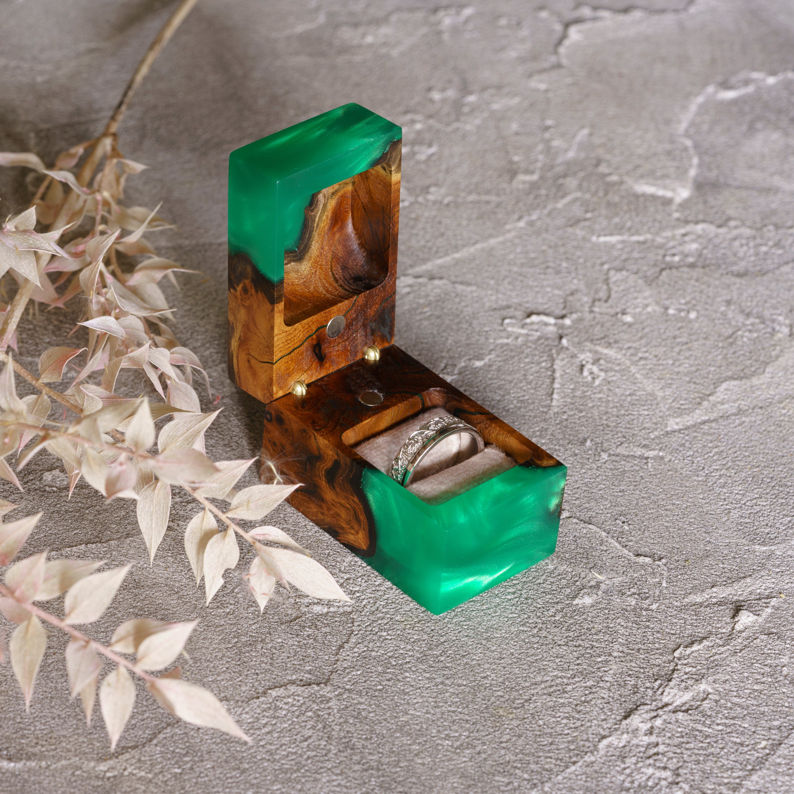 Luxury green epoxy and elm wood proposal ring box displayed open on a textured stone surface