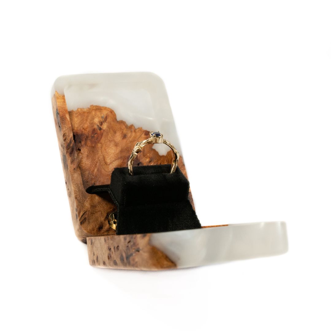 Modern platinum epoxy and elm wood proposal ring box photographed from an angled perspective