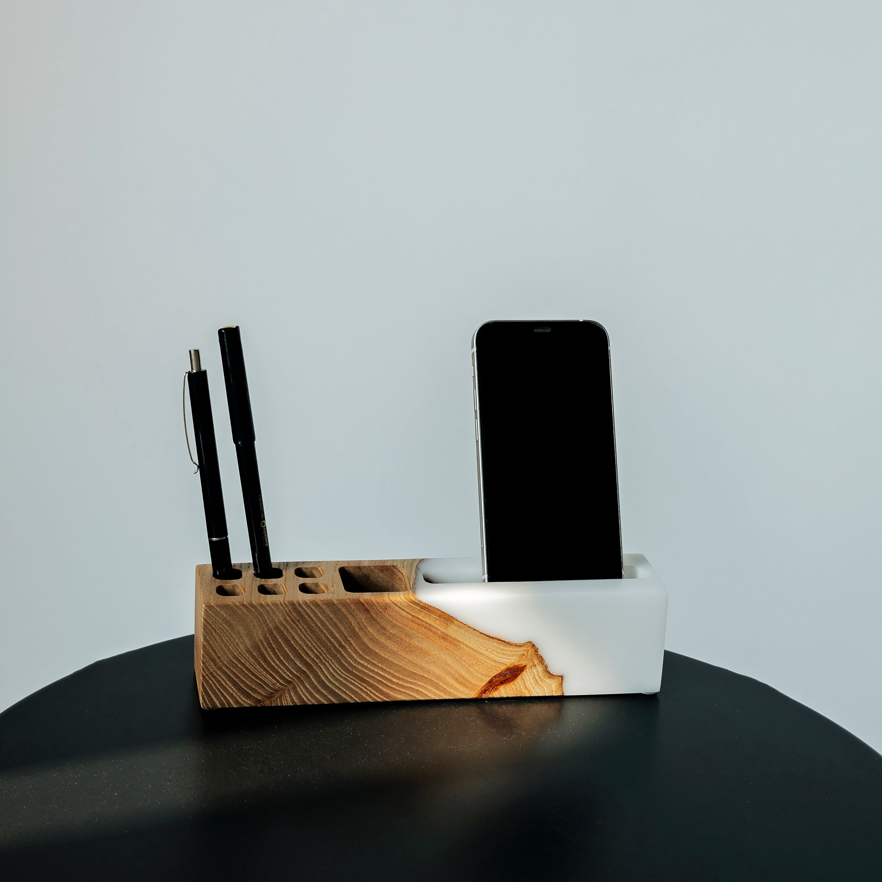 Close-up of the ELEMENT office desk organizer with phone stand and pen holder handcrafted from elm wood and white epoxy resin
