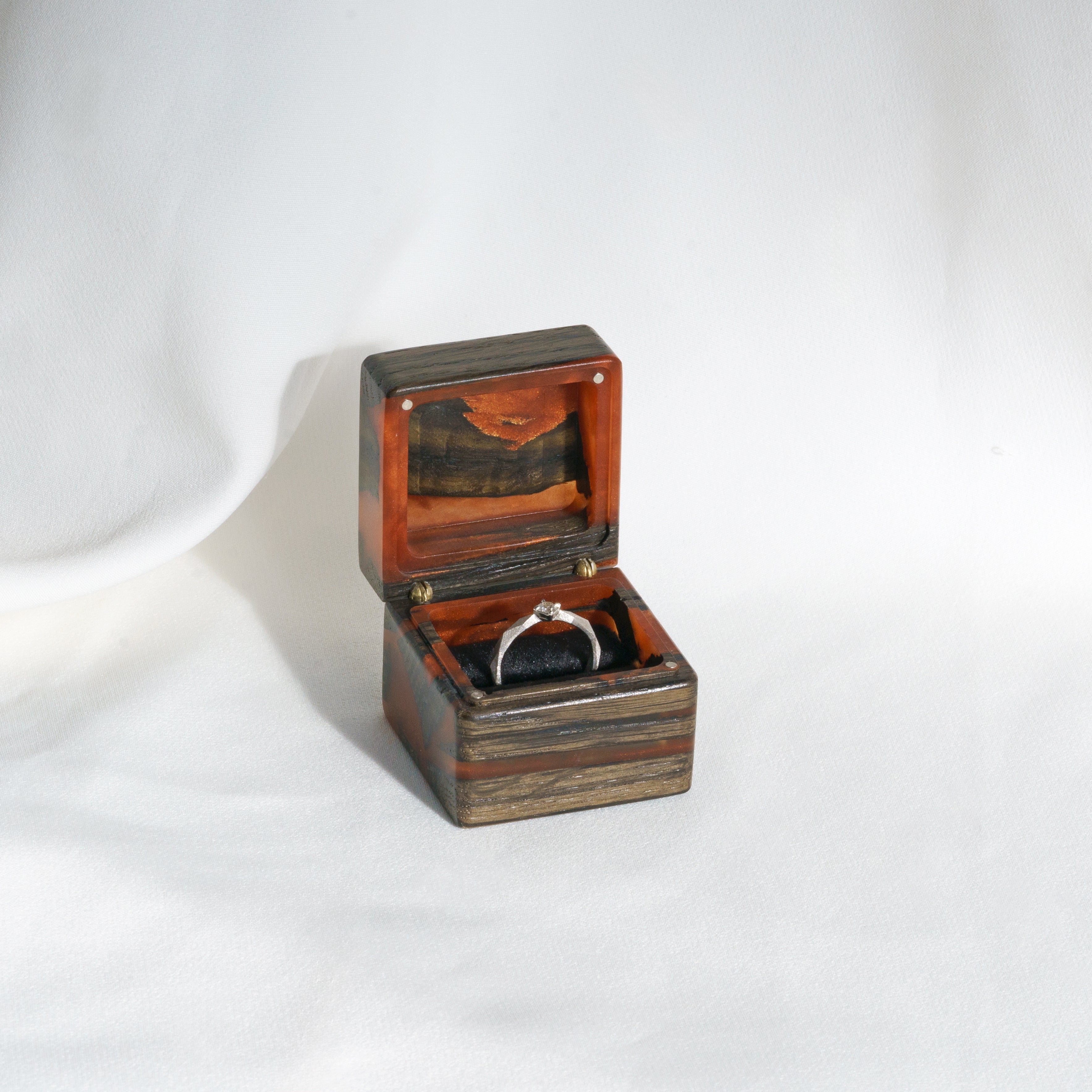 Luxury amber epoxy and bog oak wood proposal ring box displayed open on a white fabric background