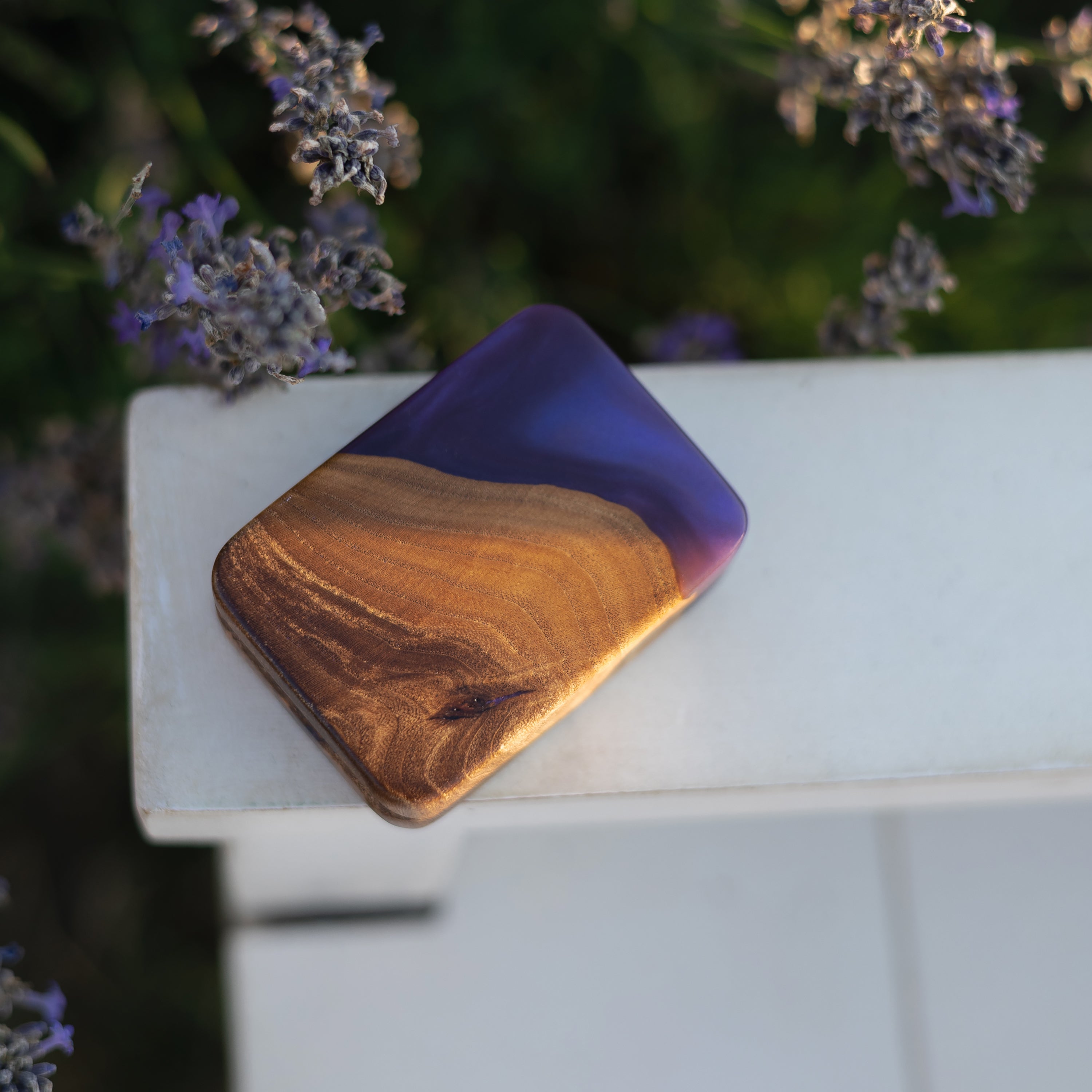Purple epoxy and elm wood engagement ring box photographed outdoors on a wooden railing