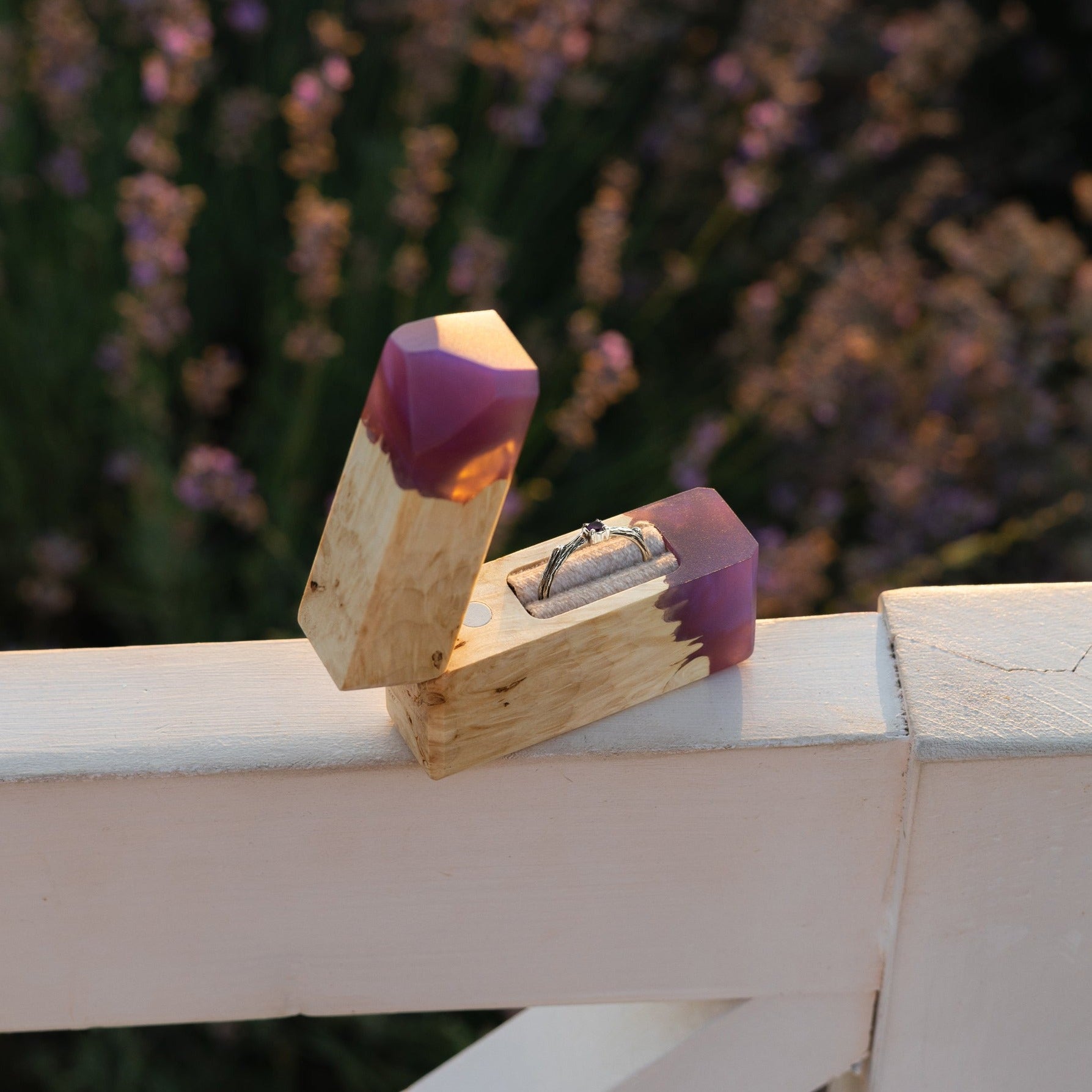 Purple epoxy and maple wood engagement ring box displayed outdoors on a white railing