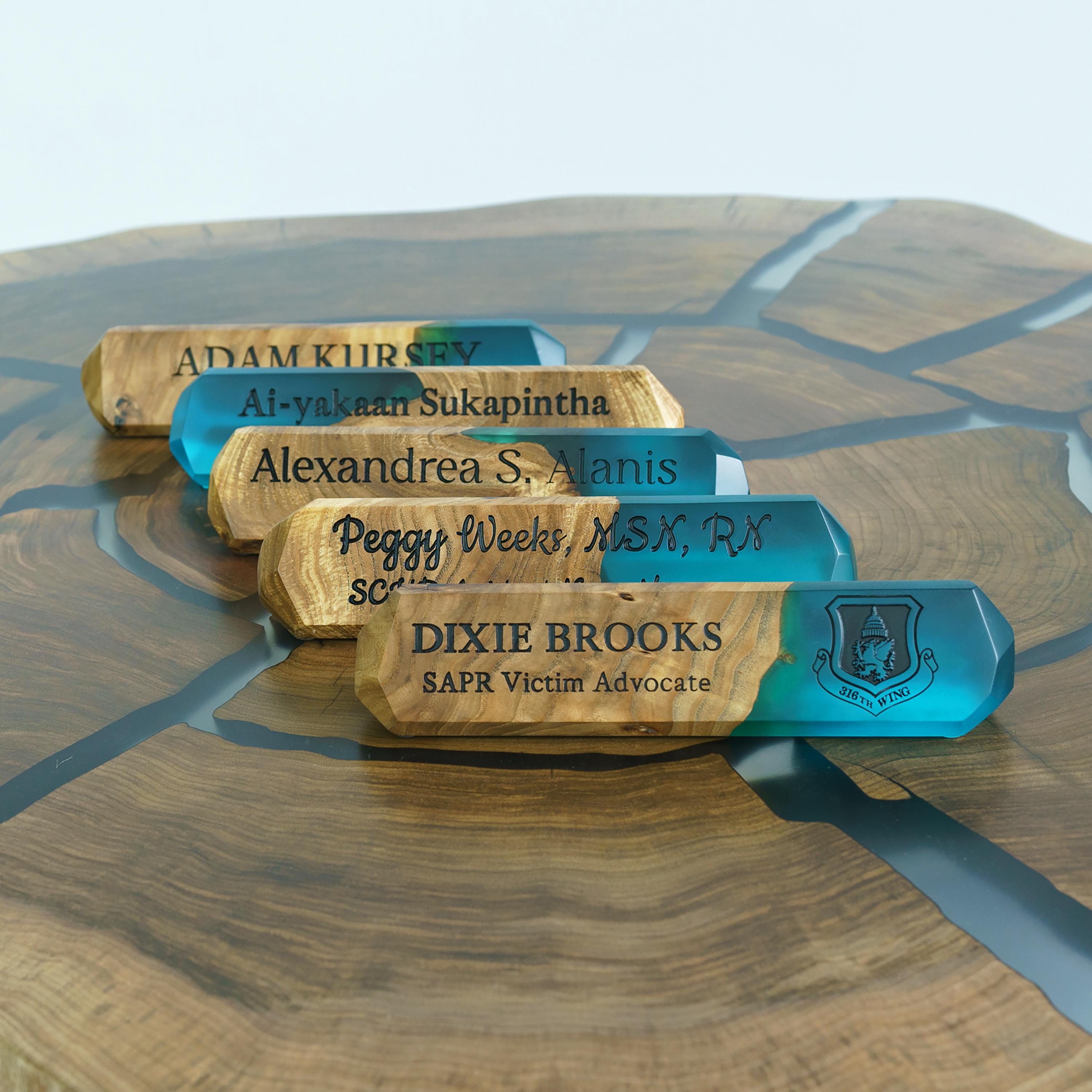 Multiple personalized wooden desk name plates with engraved names and aqua blue epoxy resin