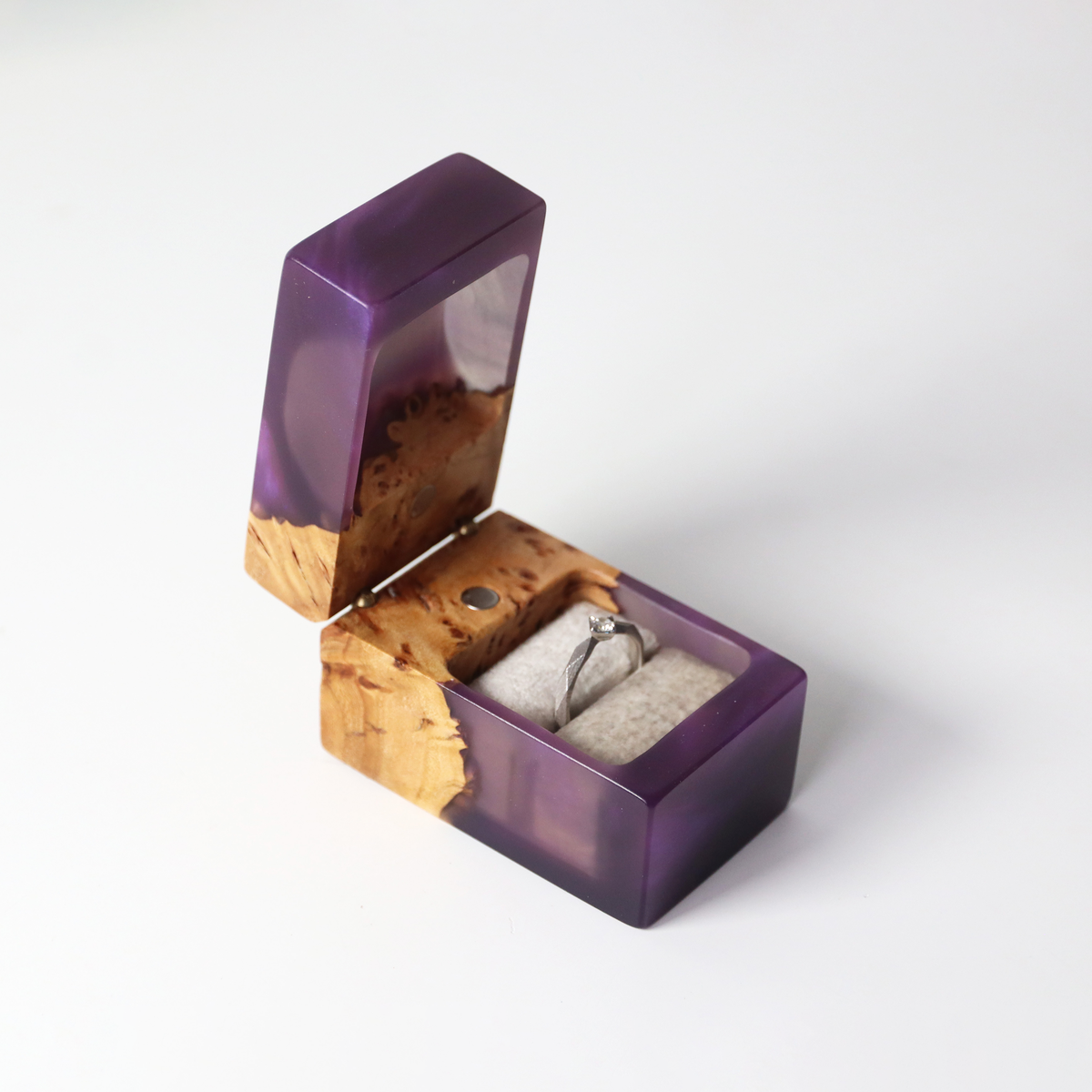 Close view of a solitaire engagement ring in the soft pillow of the purple epoxy and elm box