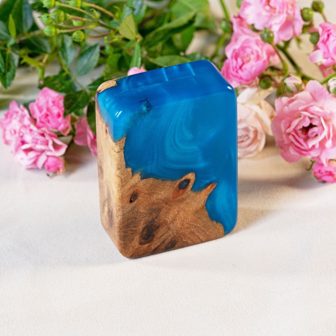 Handcrafted blue epoxy and elm wood proposal ring box photographed with pink flowers