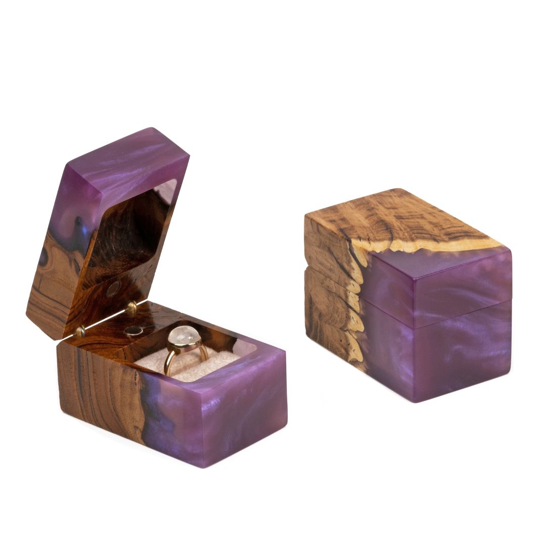 Open and closed purple epoxy and elm wood engagement ring boxes displayed together on a white background