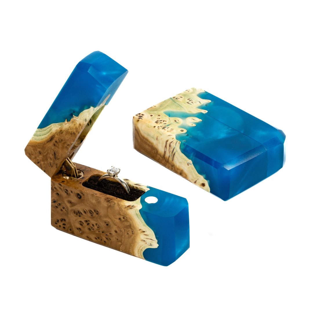 Open and closed blue epoxy and elm wood proposal ring boxes displayed together from an angled view