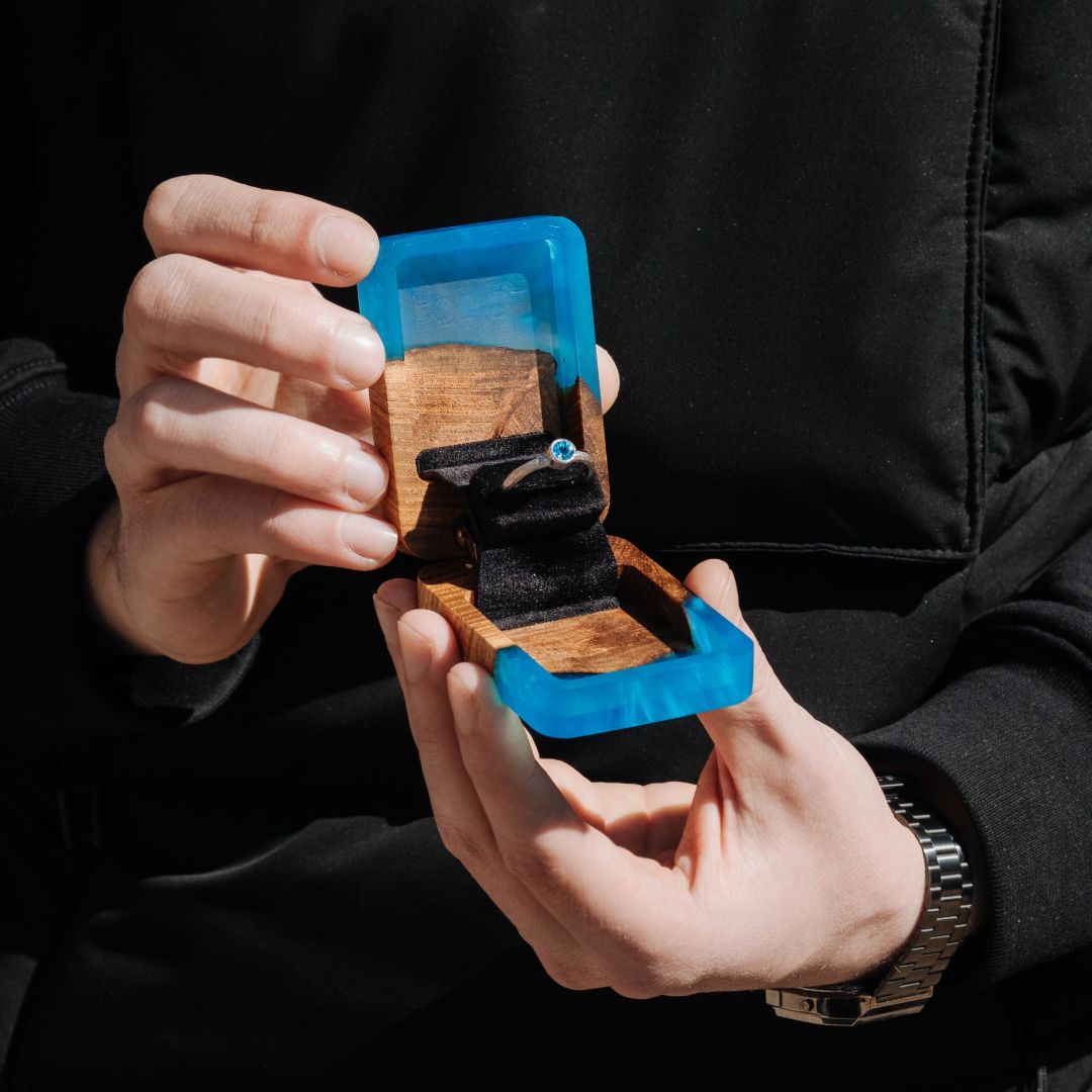 Blue epoxy and elm wood proposal ring box held in hands to show its compact size